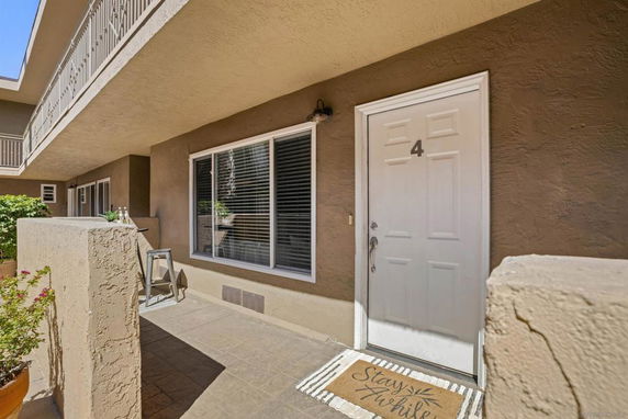 Exterior view of a building entrance with a door numbered 4 and window, surrounded by walls and a walkway.