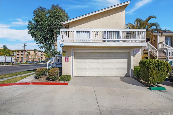 Front view of a two-story house with a white garage door and balcony.