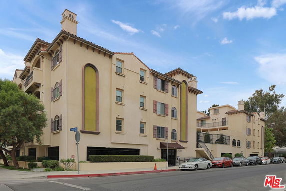Front view of a multi-story apartment building with decorative elements and a gated entrance.