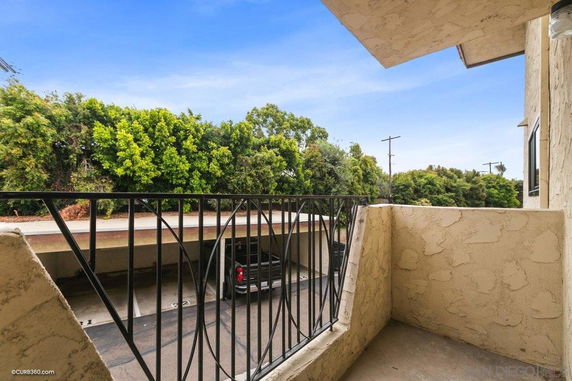 View from a balcony overlooking covered parking and greenery.