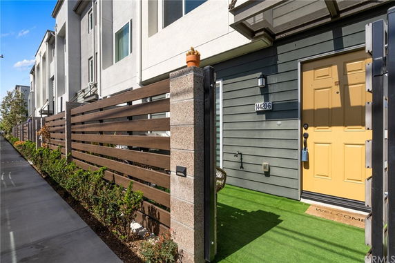 Front view of a modern multi-story residential building with a wooden fence and a yellow door.