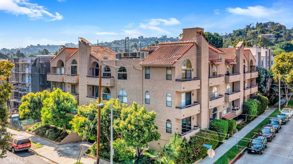 Front view of a multi-story residential building with balconies and a tile roof.