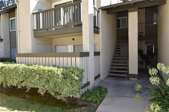 Front view of a two-story residential building with a balcony and exterior staircase.