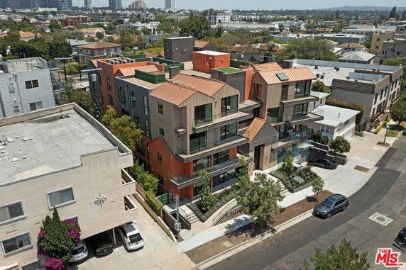 Aerial view of a modern multi-story residential building with a unique architectural design and surrounding urban landscape.