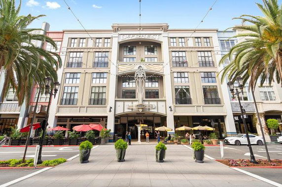 Front view of a multi-story commercial building with outdoor dining areas.