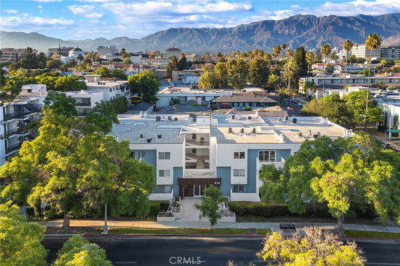 Aerial view of a modern apartment building with a flat roof and surrounding landscape.