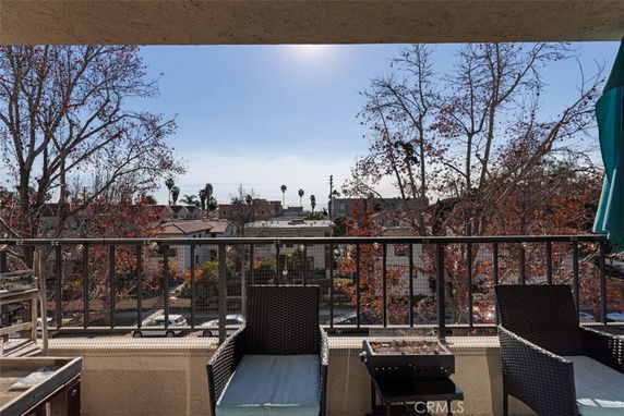 View from a balcony overlooking rooftops and distant trees.