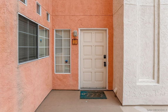 Front view of a residential entrance with beige door and windows on a textured orange wall.