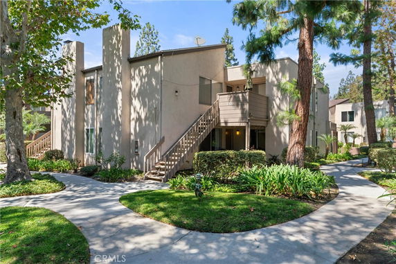 Front view of a multi-story residential building with external staircases and balconies.