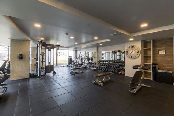 Interior view of a gym area with exercise equipment and weights.