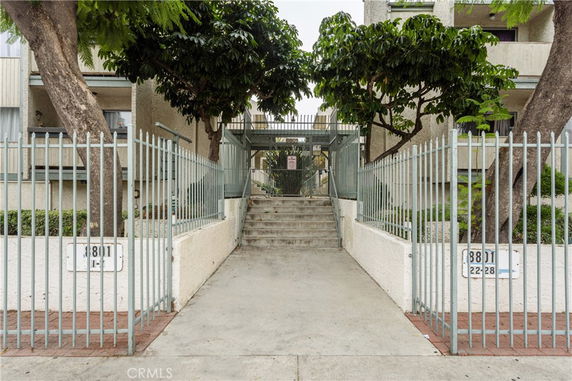 Front view of a multi-story building with gated entrance and stairs leading up.