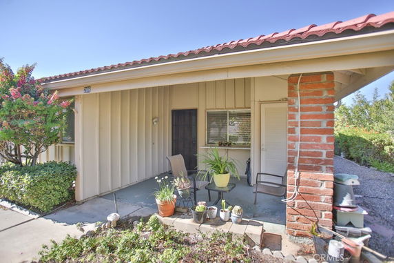 Front view of a single-story house with a small porch and potted plants.