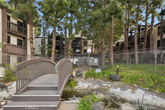 Front view of a multi-story apartment building with wooden balconies and trees in front.