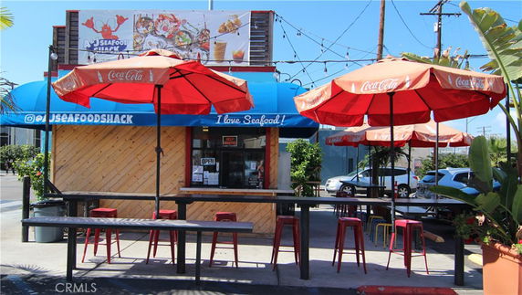 Front view of a seafood shack with outdoor seating and umbrellas.