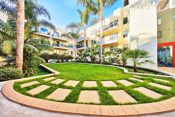 Courtyard view of a multi-story residential building with balconies and landscaped greenery.