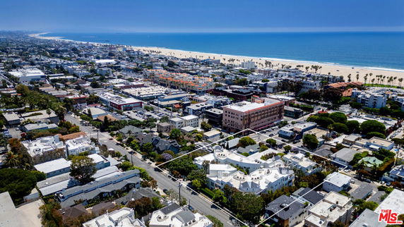 Aerial view of a coastal cityscape with residential and commercial buildings, beach, and ocean.