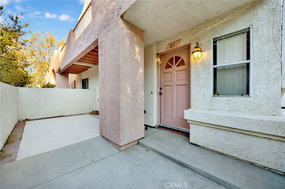 Front view of a house with a textured exterior and a pink front door.