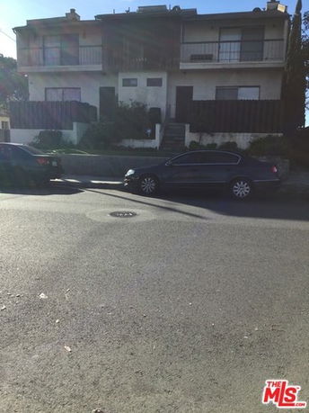 Front view of a two-story residential building with parked cars in front.