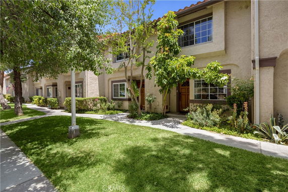 Front view of a two-story residential building with multiple units and a shared walkway.