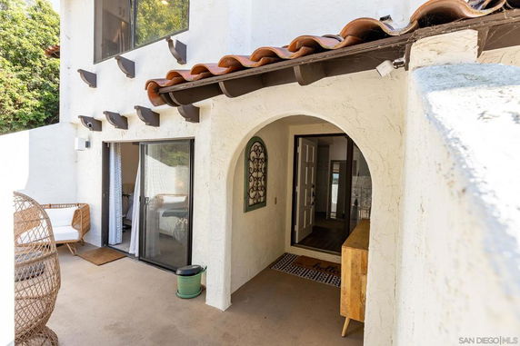 Exterior view of a house with arched entrance and sliding glass doors.