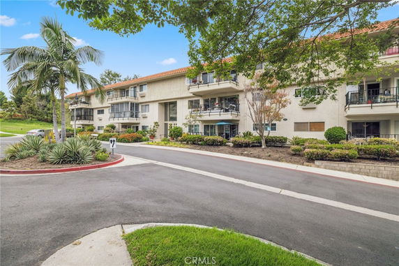 Front view of a multi-story residential building with balconies and a driveway.