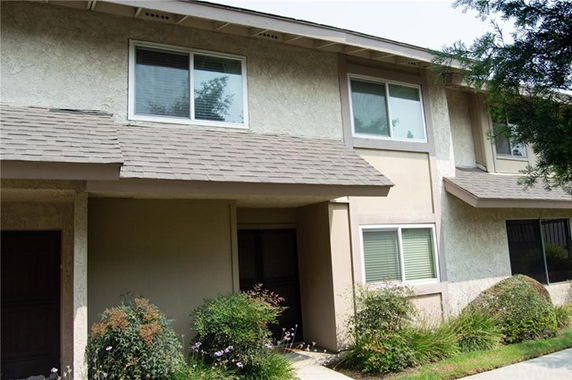 Front view of a two-story house with a brown shingle roof and two large windows.