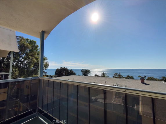 Panoramic view from a balcony overlooking the ocean and rooftops.