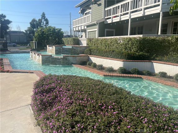 View of a swimming pool area with cascading water and adjacent building.