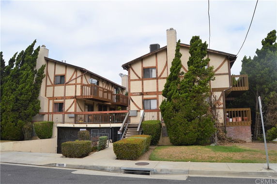 Front view of a two-story apartment building with balconies and decorative beam work.