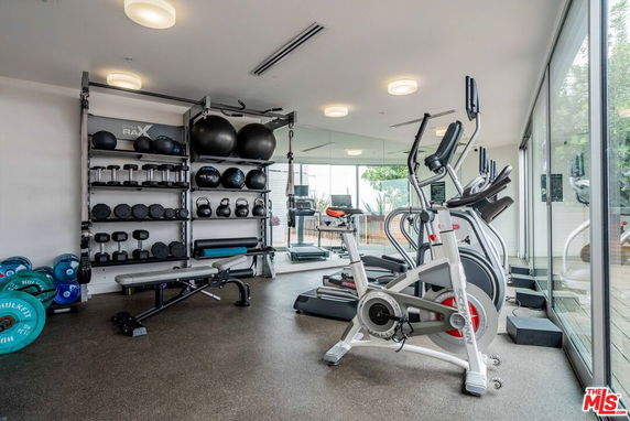 Indoor gym area with exercise equipment and weights.