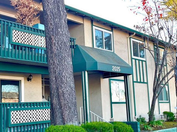 Front view of a two-story building with balconies and green accents.