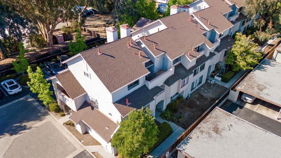 Aerial view of a multi-story residential building with sloped roofs and multiple chimneys.