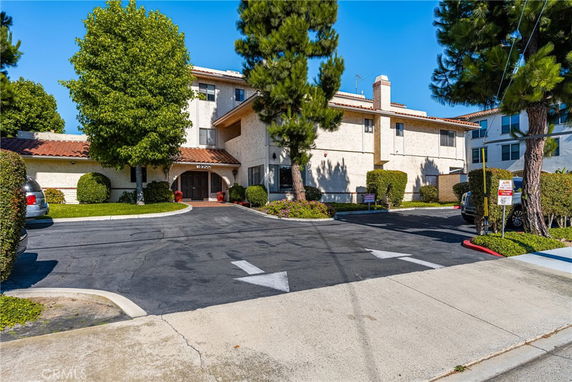 Front view of a two-story building with a Spanish tile roof and entrance driveway.