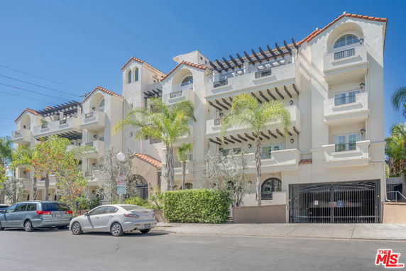 Front view of a multi-story residential building with balconies and a gated entrance.