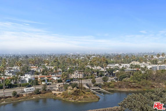 Panoramic view of a cityscape with a body of water, roads, and residential buildings.