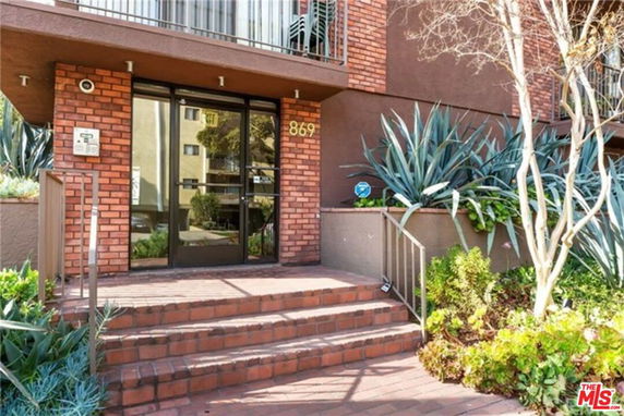 Front view of a building entrance with brickwork and glass door.