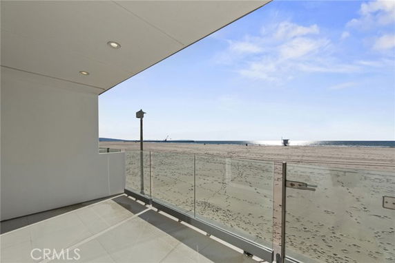 Balcony view with glass railing overlooking a beach and ocean.