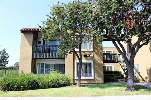 Front view of a two-story apartment building with a balcony and external staircase.
