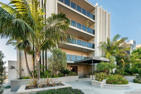 Front view of a multi-story building with balconies and a covered entrance.