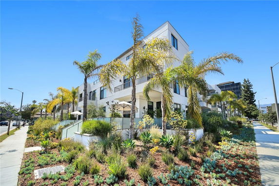 Front view of a modern multi-story building with large windows and a landscaped garden.