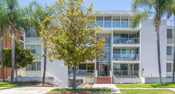 Front view of a multi-story building with glass balconies and a central entrance.