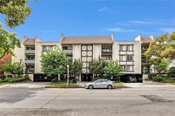 Front view of a multi-story building with balconies and a tiled roof.