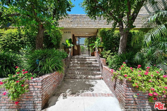Front view of an entrance with brick steps and plants leading to a building.