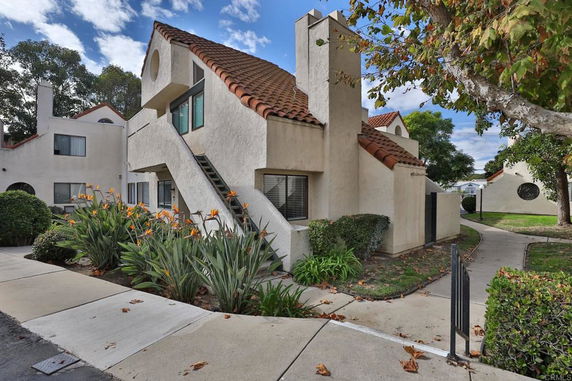 Front view of a two-story house with tile roofing and staircase.