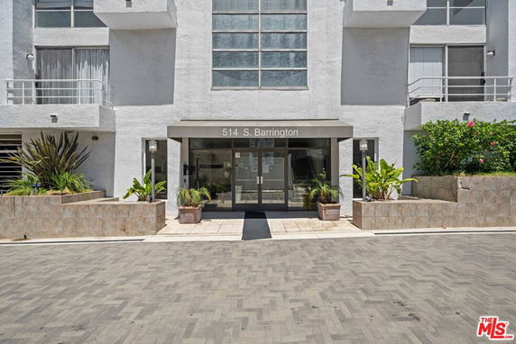 Front view of a modern building entrance with glass doors and potted plants.