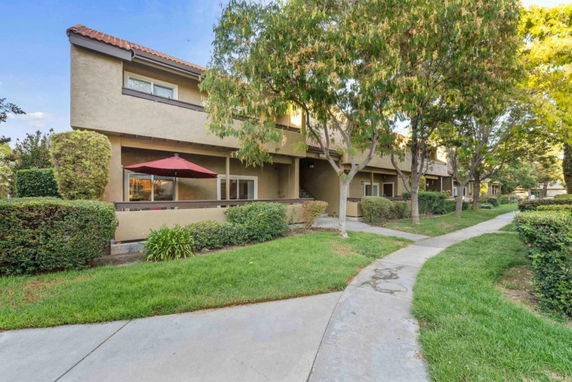Front view of a residential building with a sidewalk and trees.
