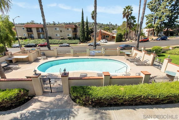 Outdoor swimming pool with surrounding lounge chairs and fencing.