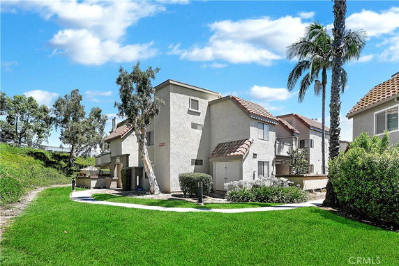Front view of a multi-story house with a tiled roof and beige stucco exterior.