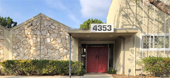 Front view of a building with a stone wall facade and a red double door entrance.