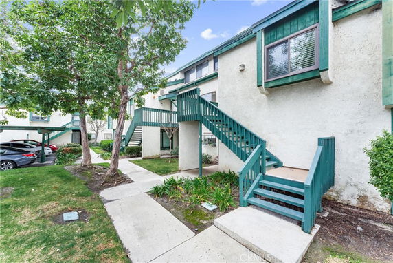 Front view of a two-story building with exterior staircase and green accents